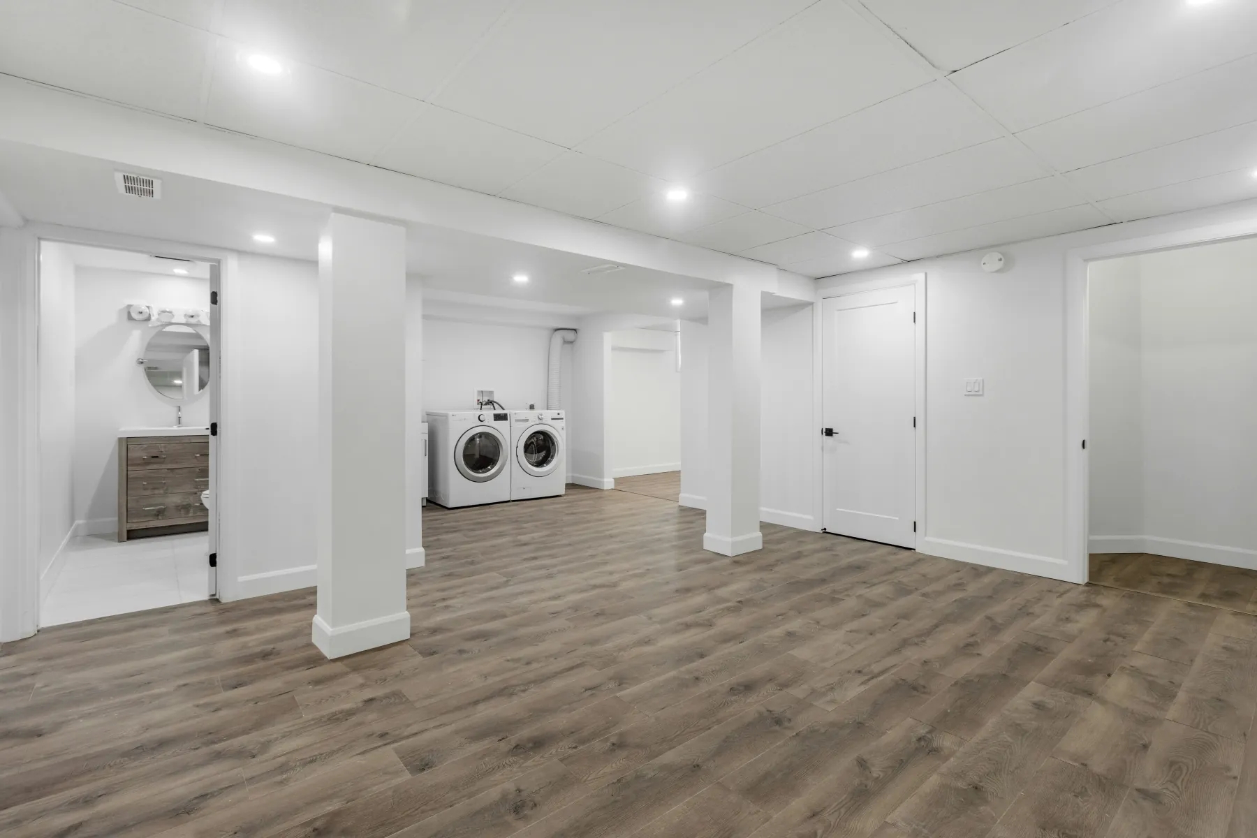 Clean, open basement with fresh floors and a laundry area